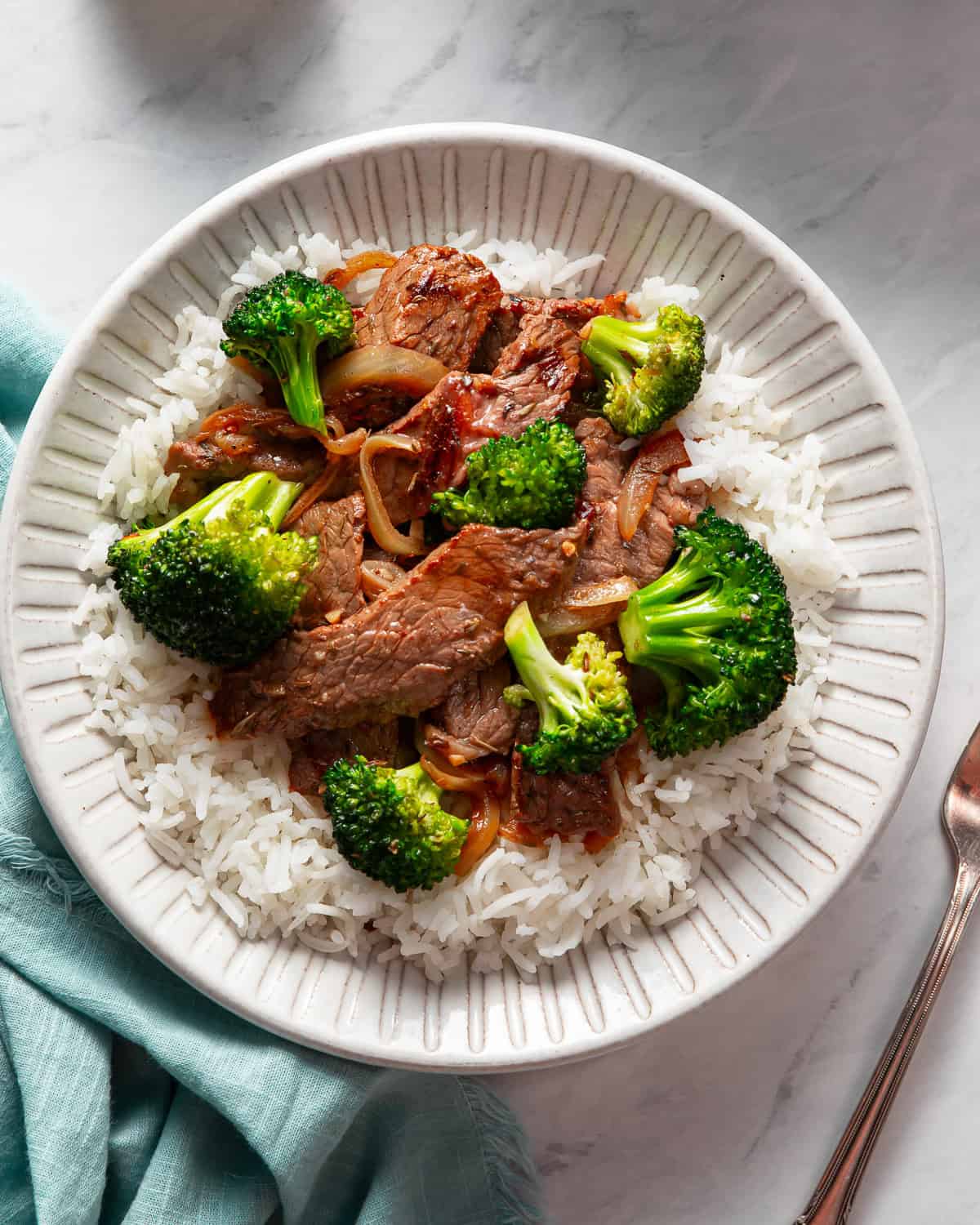 Steak and broccoli plated on a bed of white rice.