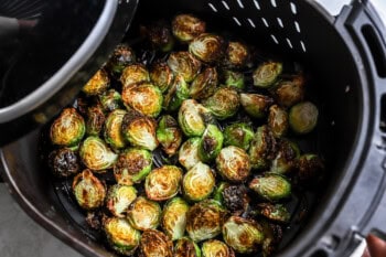 halved brussels sprouts cooking in an air fryer.