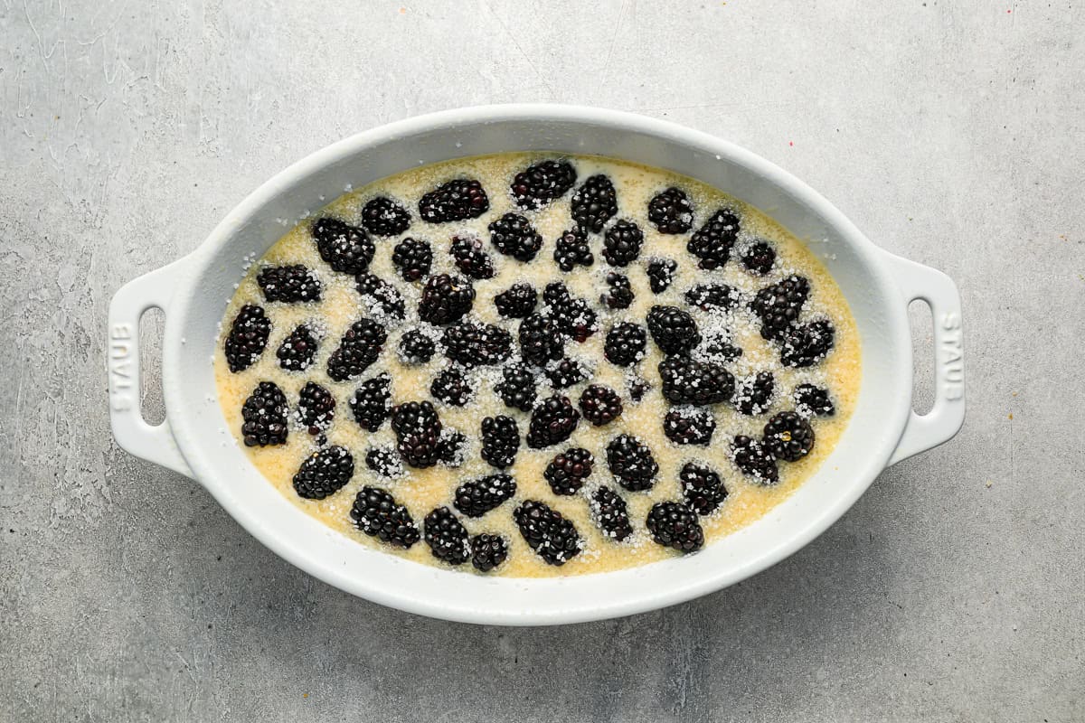Unbaked cobbler topped with blackberries in a white ceramic dish.