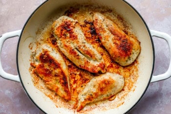 Four chicken breasts cooking in a pot.