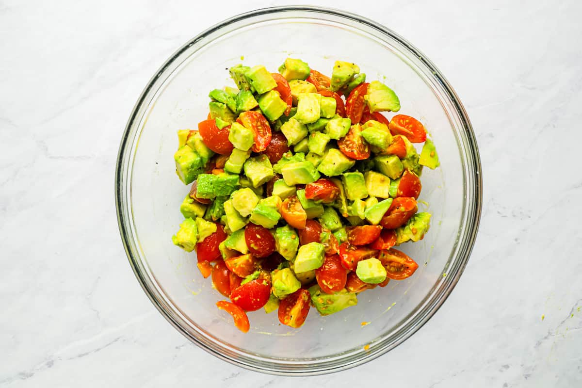 Chopped tomato and avocado salsa in a glass mixing bowl.