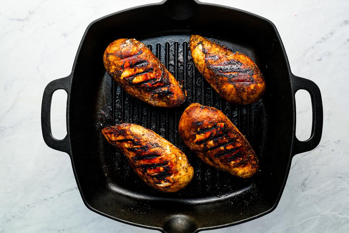 Balsamic marinated chicken breasts grilling in a pan.