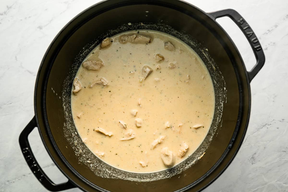 Pieces of chicken submerged in a creamy sauce.