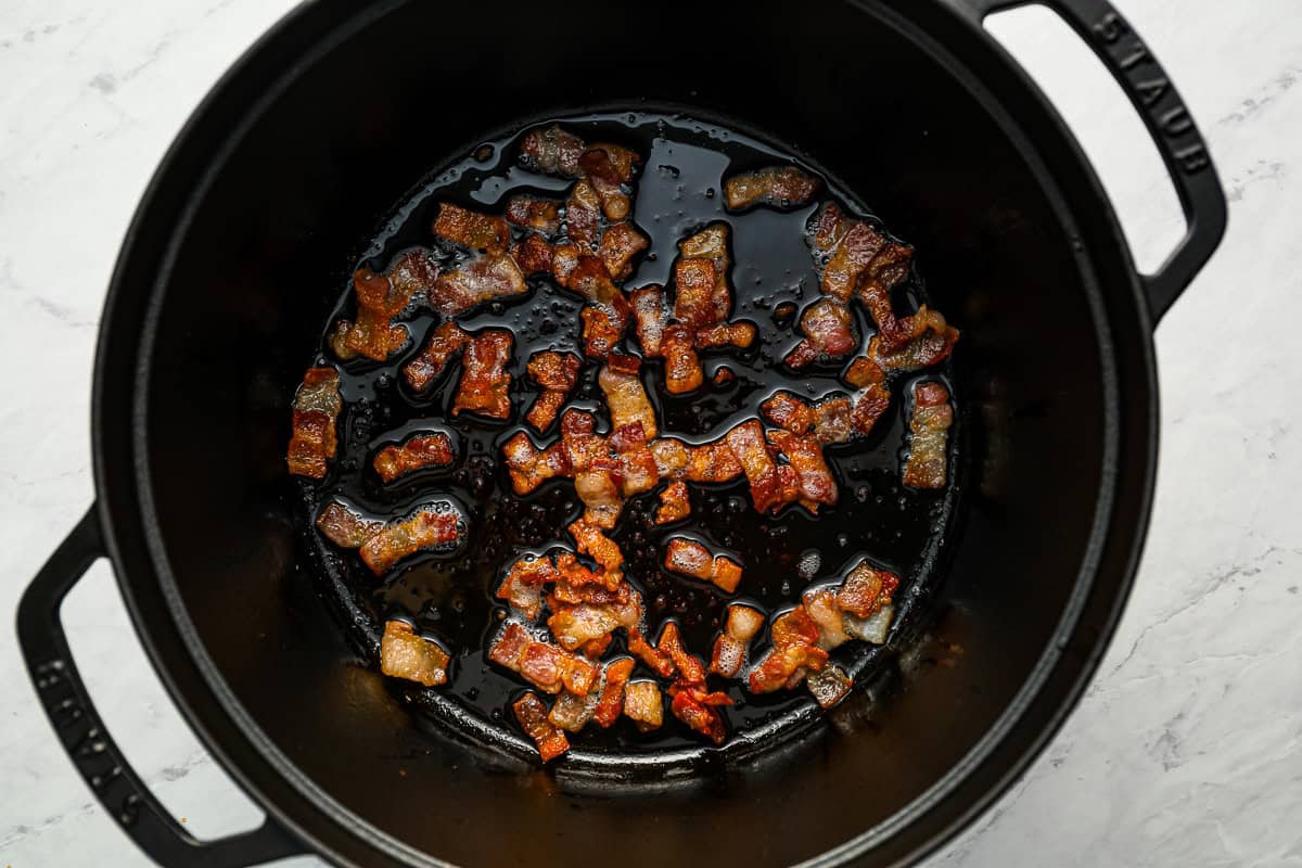 Pieces of bacon cooking in a pot.