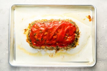 glaze spooned over partially baked meatloaf on a baking sheet.