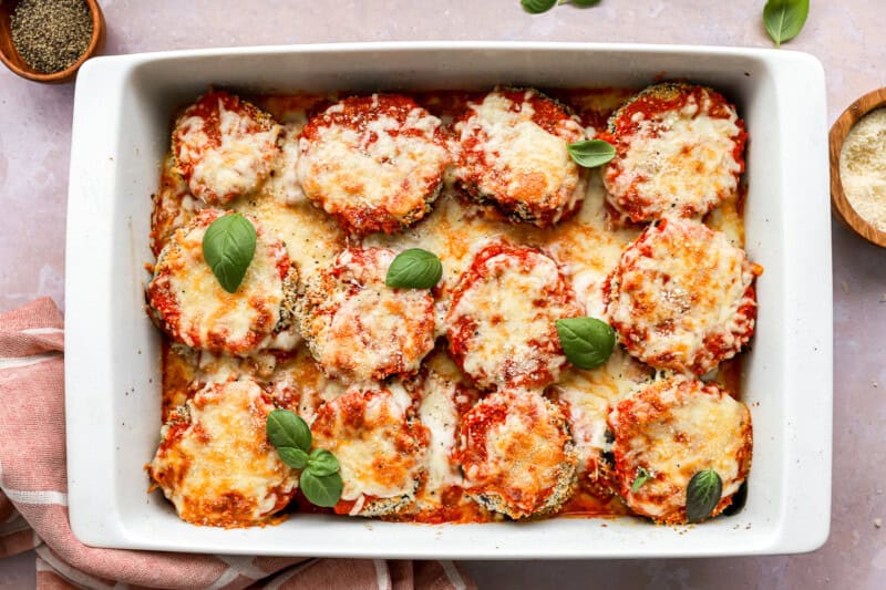 baked eggplant parmesan in a baking pan topped with basil.