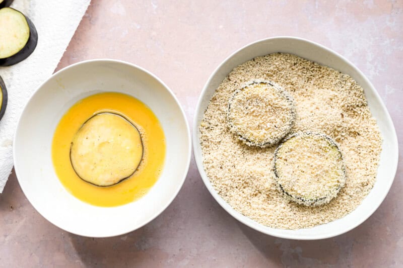 dredging slices of eggplant in egg and panko breadcrumbs.