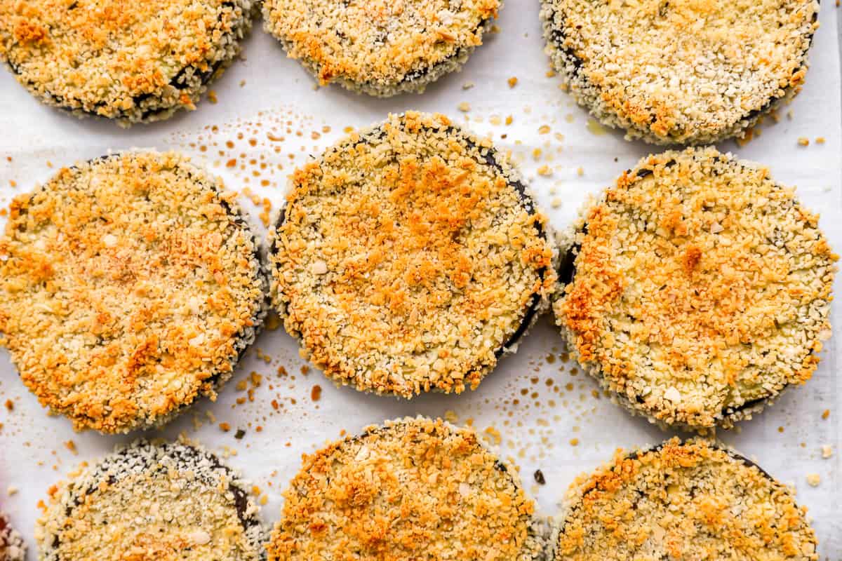 close up of baked breaded eggplant slices on a baking sheet.