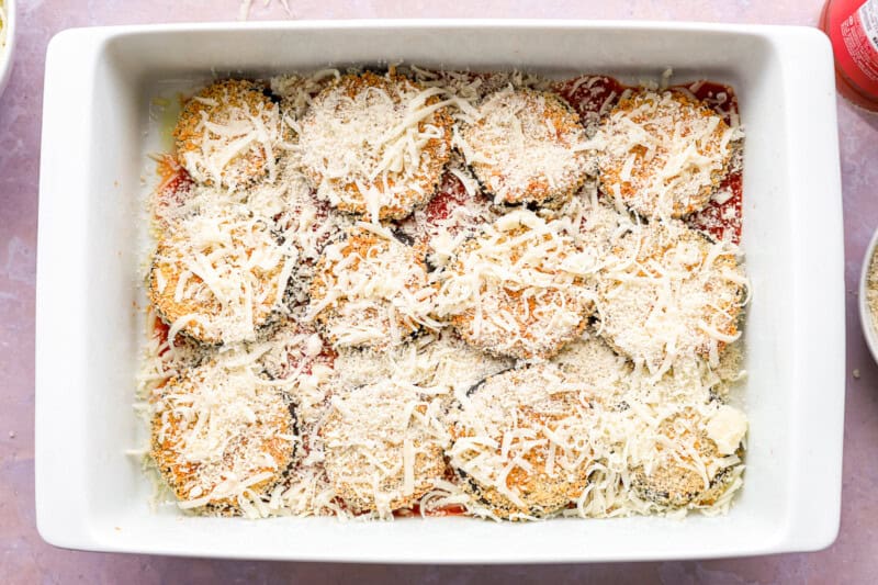 cheese sprinkled over eggplant in a baking pan.