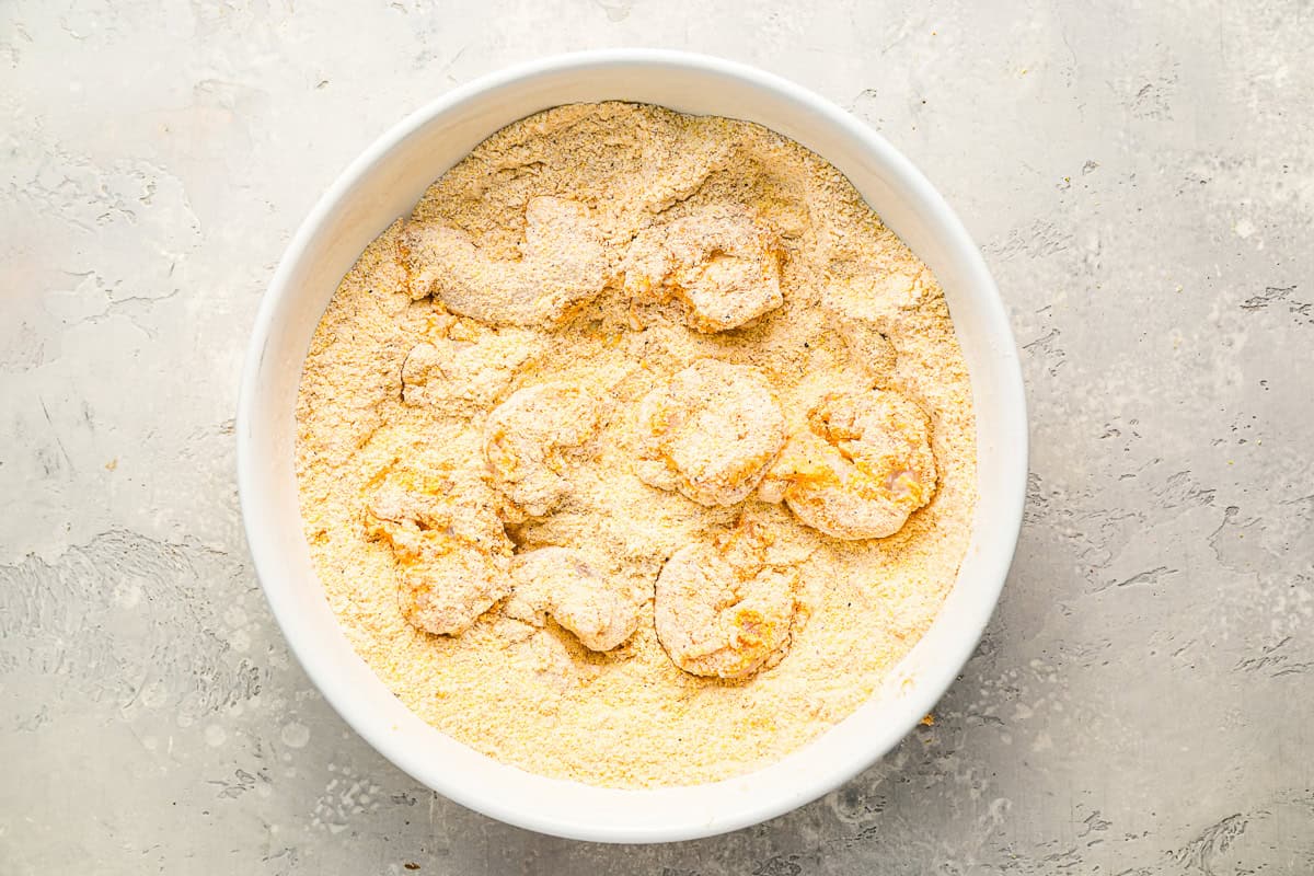 shrimp tossed in seasoned flour and cornmeal in a bowl.