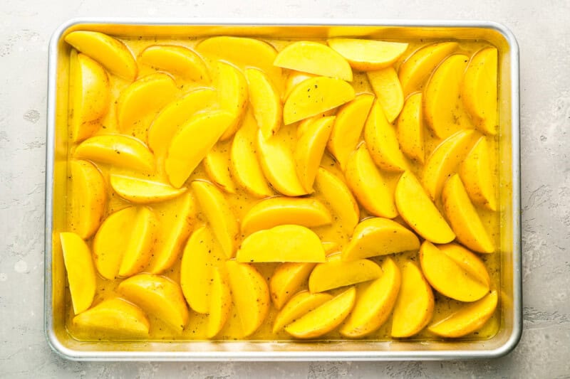 potato wedges in broth on a baking sheet.