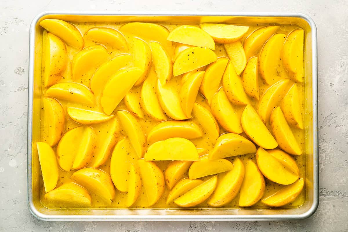 potato wedges in broth on a baking sheet.