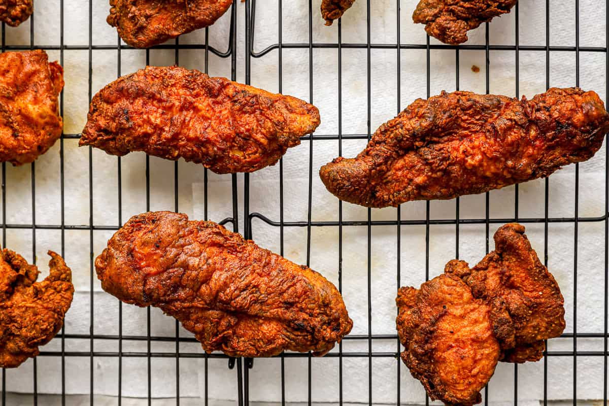 nashville hot chicken pieces on a wire rack set in a baking sheet.