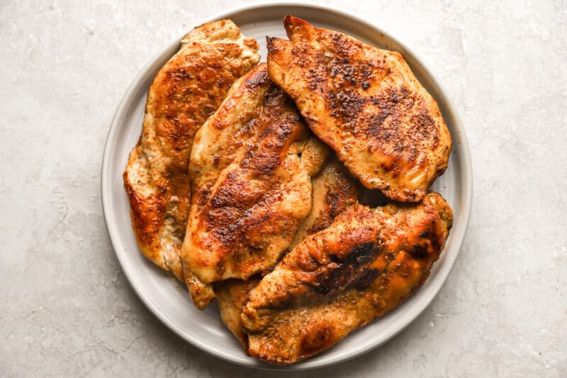 cooked thin sliced chicken breasts on a white plate.