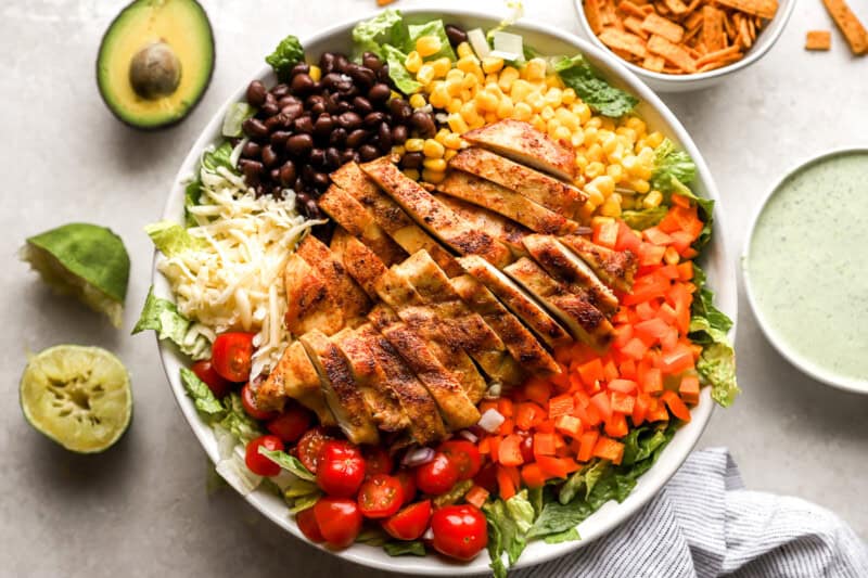 ingredients for southwest salad laid over lettuce in a white bowl.