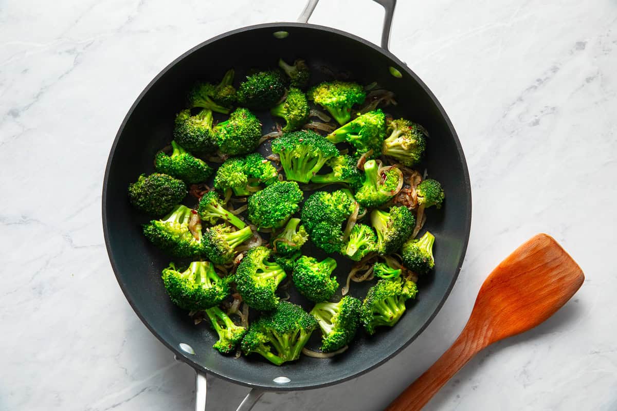 Broccoli florets cooking in a skillet.