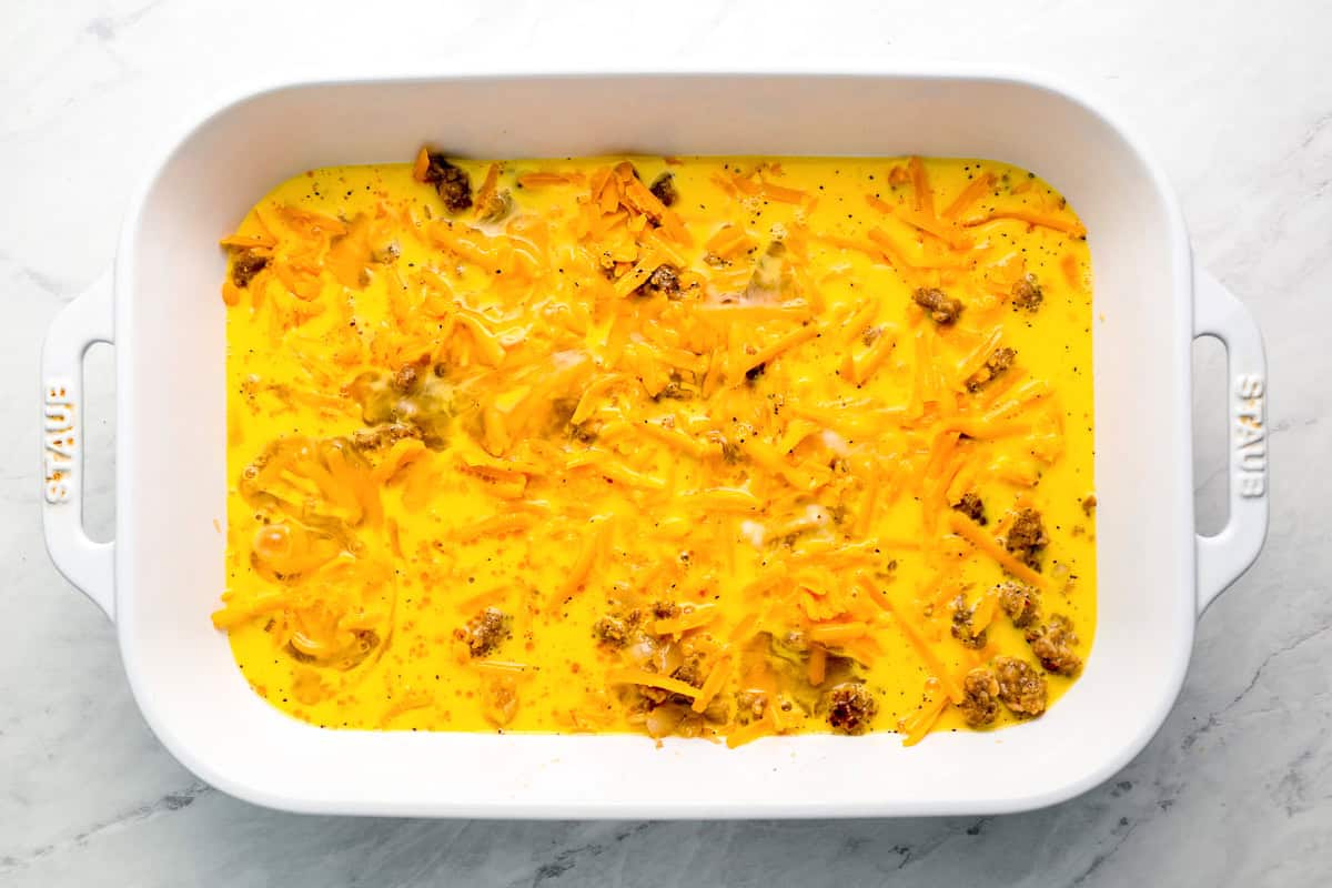 eggs poured over sausage and cheese in a casserole dish.