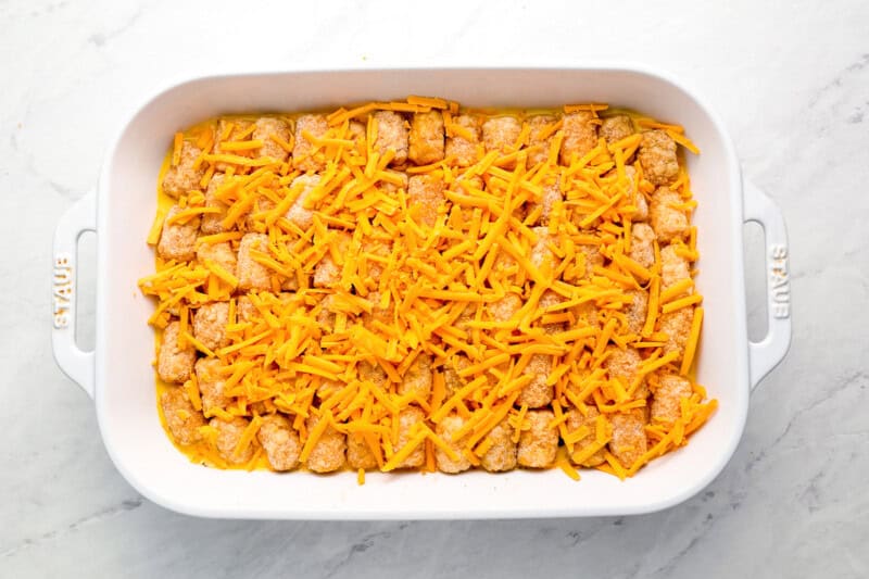 cheese sprinkled over tater tot breakfast casserole in a baking dish.