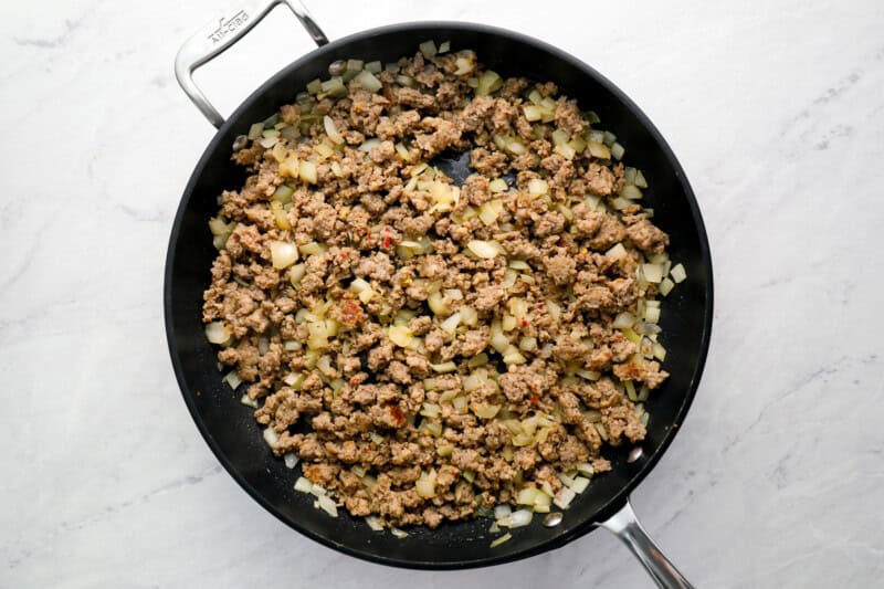 crumbled cooked sausage and onions in a pan.