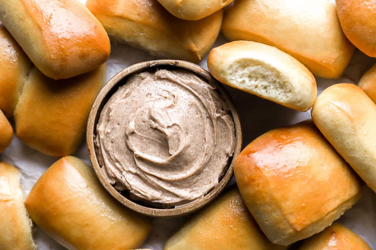 close up view of a bowl of texas roadhouse butter surrounded by rolls.