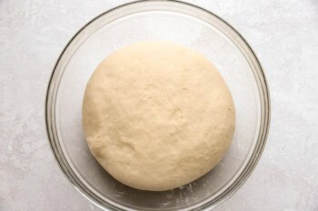 a risen ball of dough in a glass bowl.