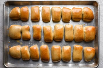 24 texas roadhouse rolls on a baking sheet.