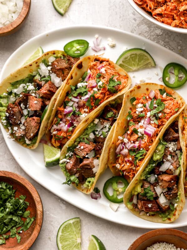 6 street tacos on a white platter.