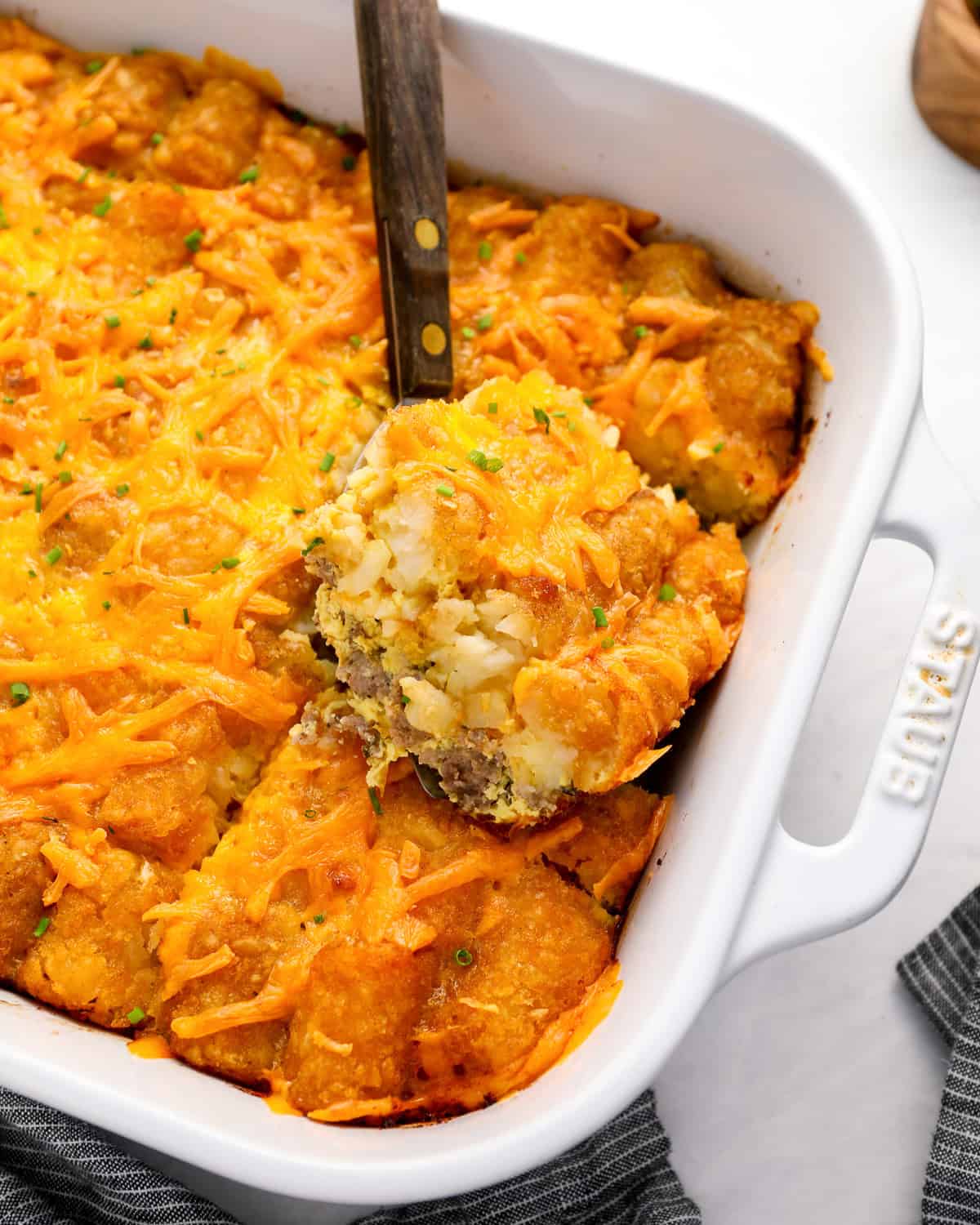 a serving of tater tot breakfast casserole on a spatula resting on the casserole.