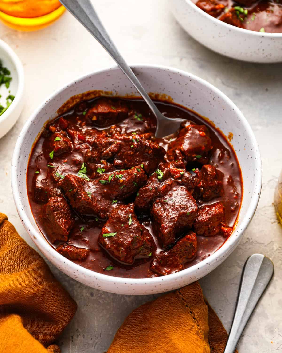 a serving of texas chili in a white bowl with a spoon.