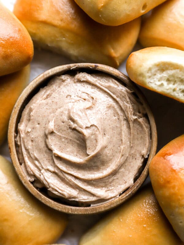 overhead view of texas roadhouse honey cinnamon butter in a bowl surrounded by rolls.