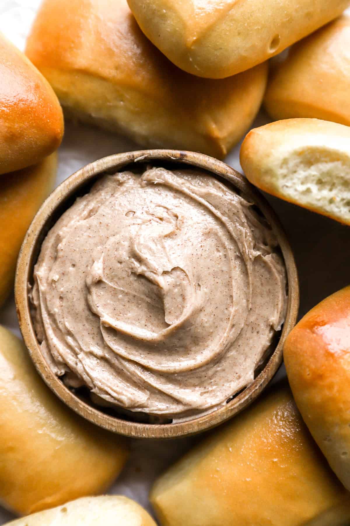 overhead view of texas roadhouse honey cinnamon butter in a bowl surrounded by rolls.