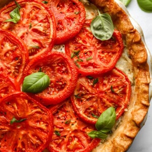 partial overhead view of a tomato pie topped with basil.