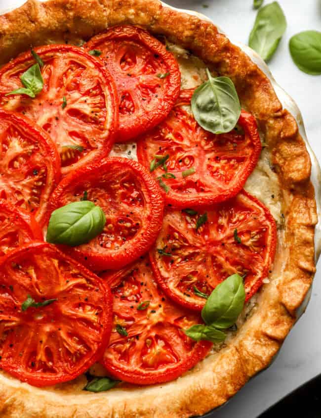 partial overhead view of a tomato pie topped with basil.
