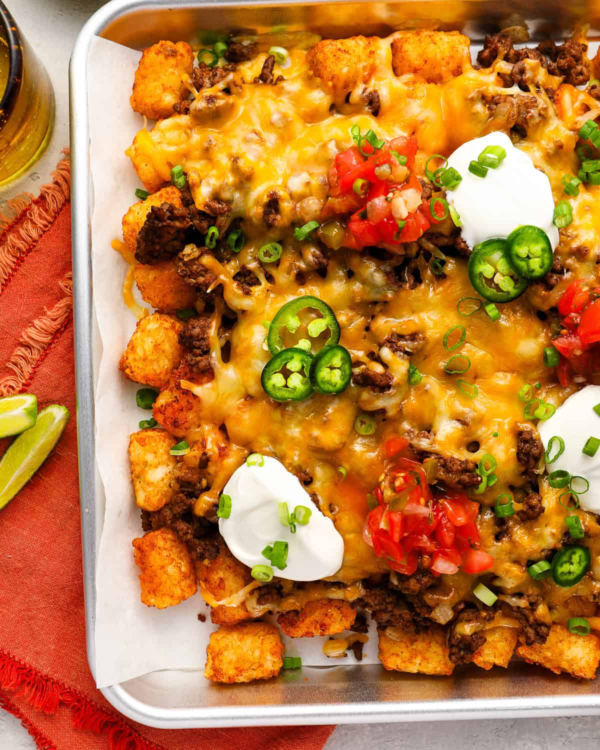 overhead view of loaded tater tots (totchos) on a baking sheet.