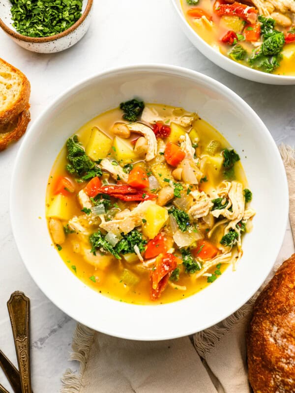 overhead view of a serving of tuscan chicken soup in a white bowl.