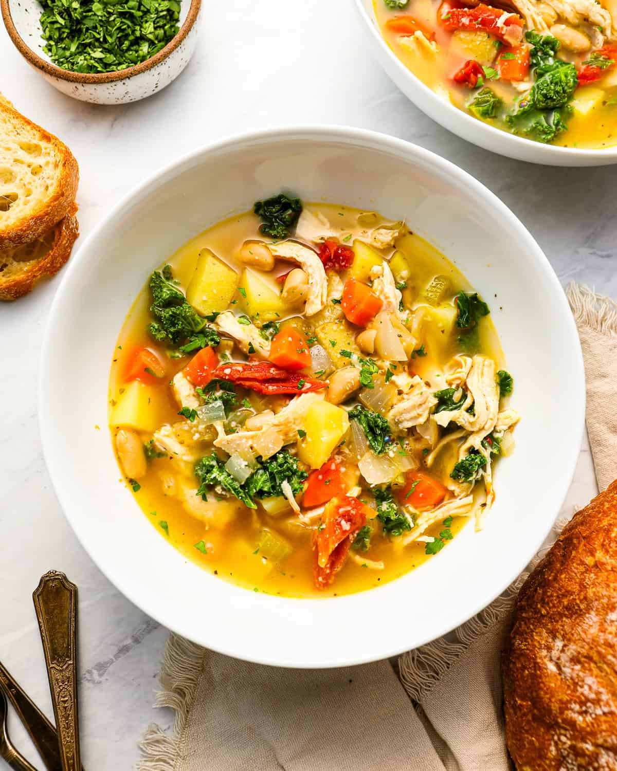 overhead view of a serving of tuscan chicken soup in a white bowl.