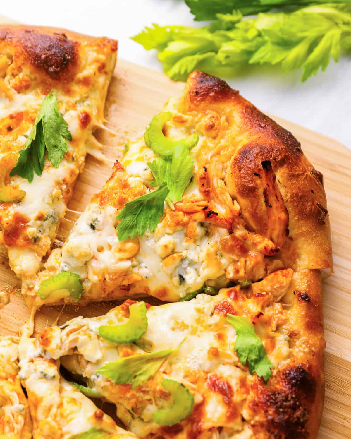 close-up of sliced buffalo chicken pizza on a wood pizza peel.