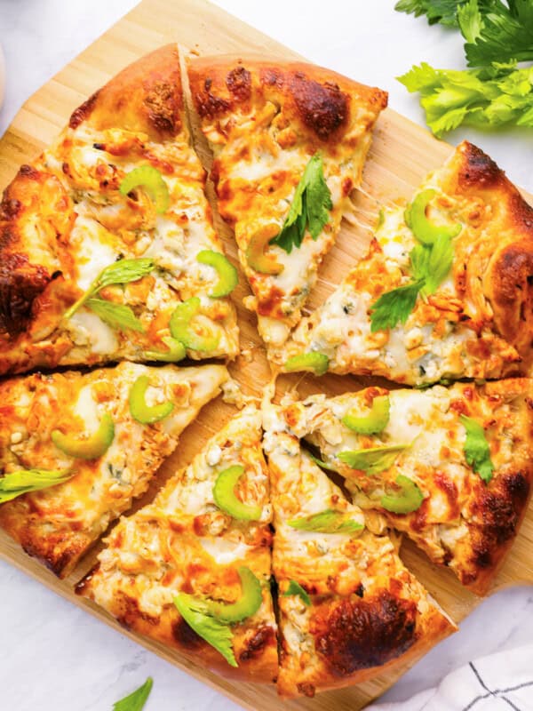 overhead view of a sliced buffalo chicken pizza on a wood pizza peel.