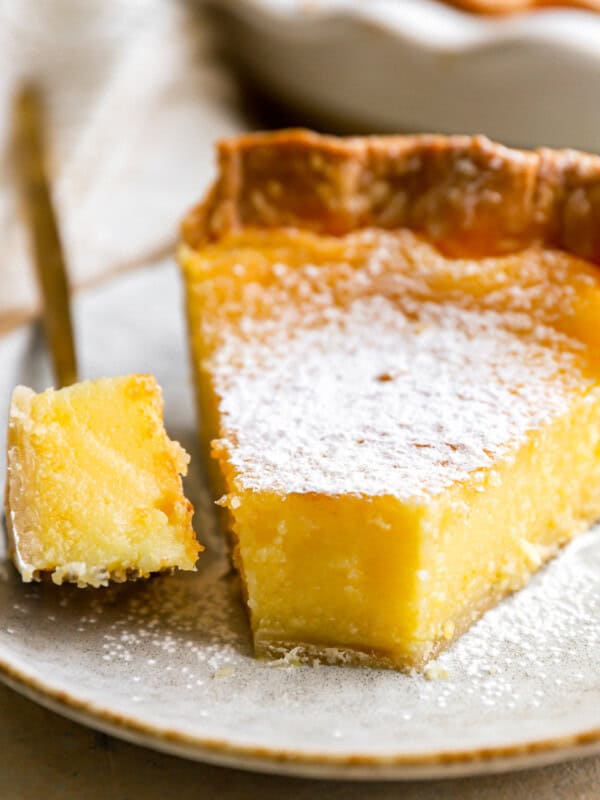 a forkful of chess pie next to a slice on a speckled plate.