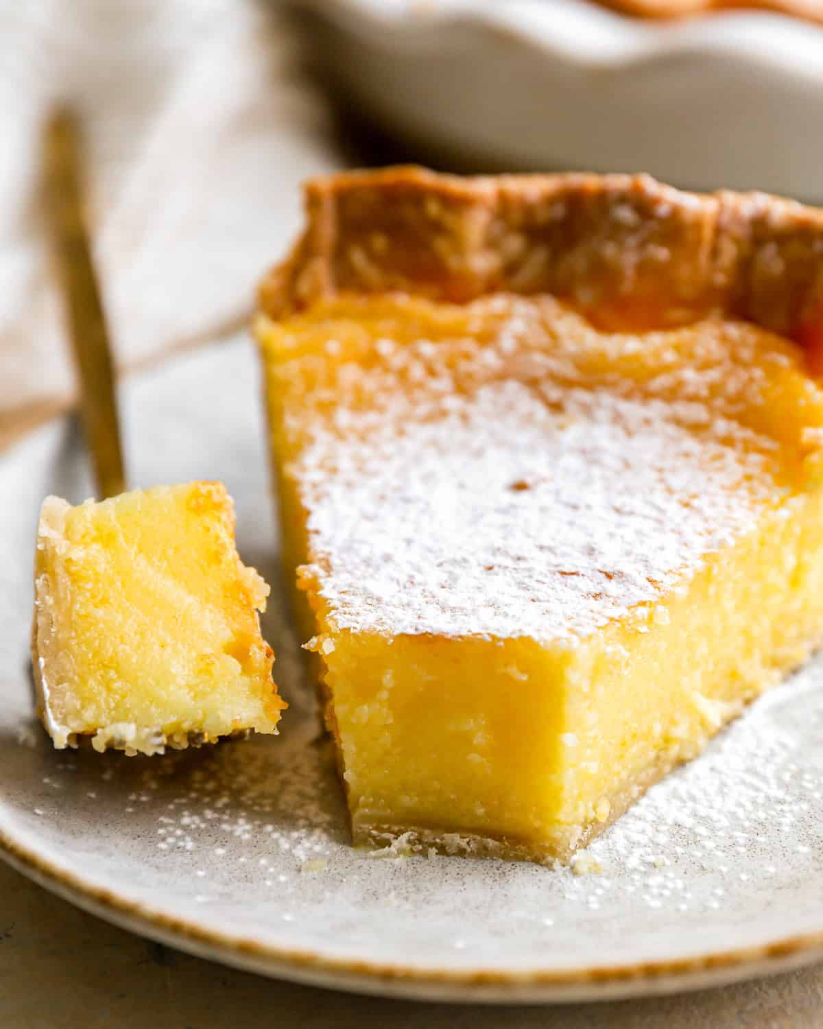 a forkful of chess pie next to a slice on a speckled plate.