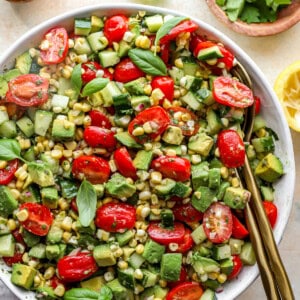 close up overhead view of avocado salad in a white bowl with a serving spoon.