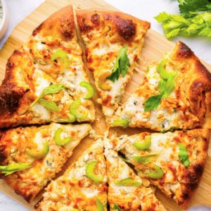 overhead view of a sliced buffalo chicken pizza on a wood pizza peel.