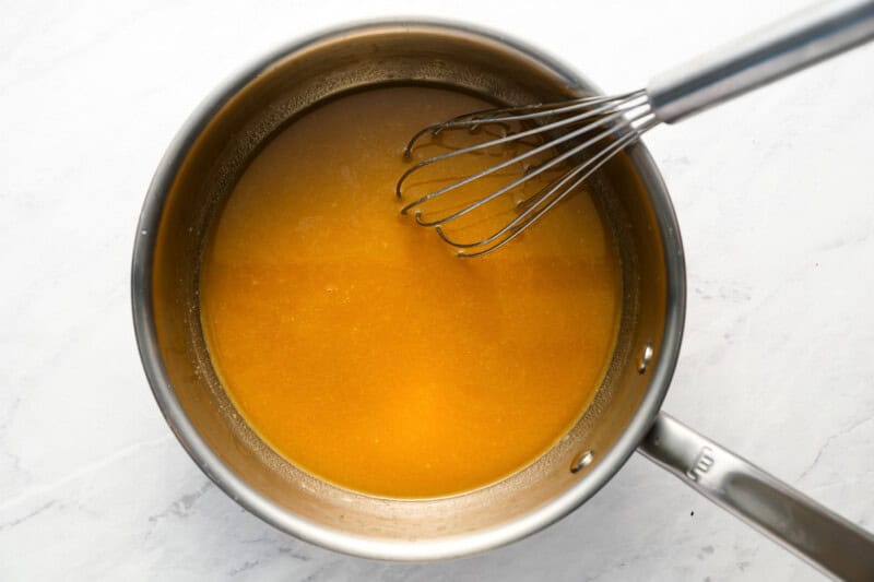 stirring beef broth into a roux in a pot.