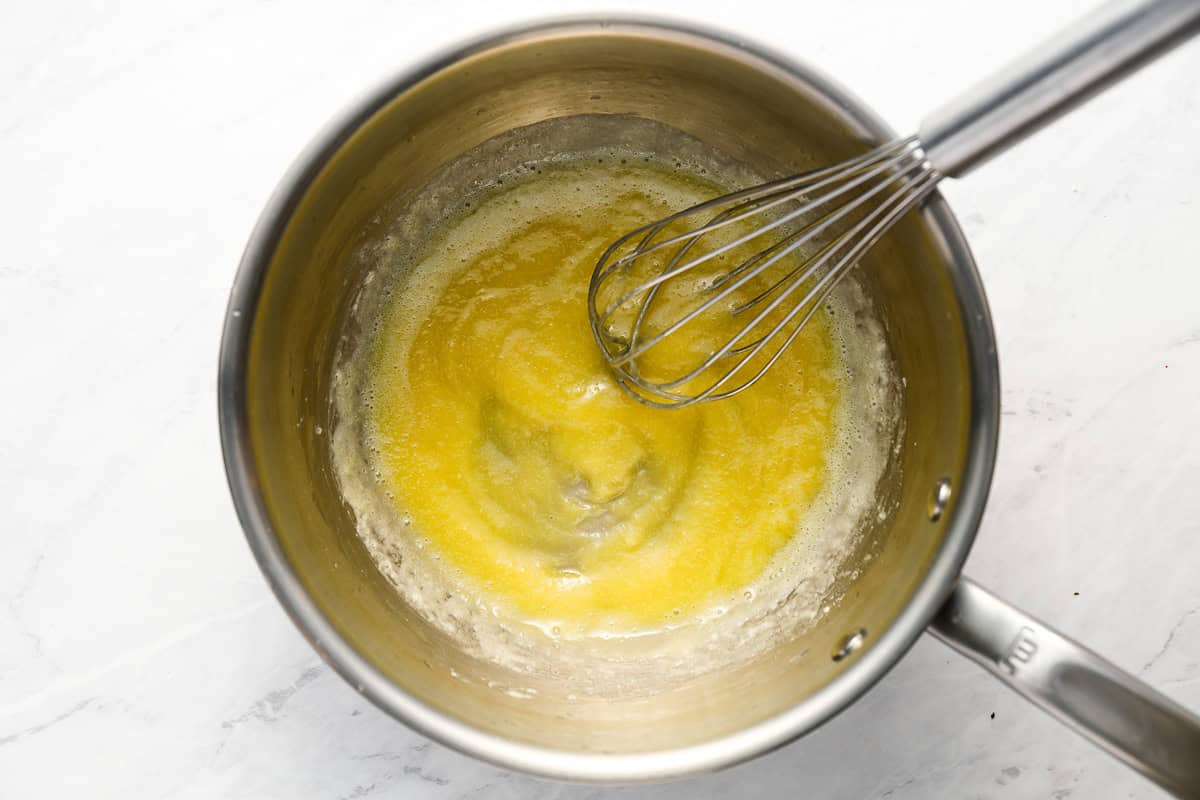 whisking a roux in a pot.