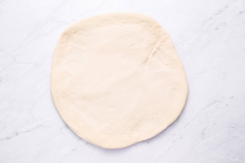 pizza dough spread in a circle.