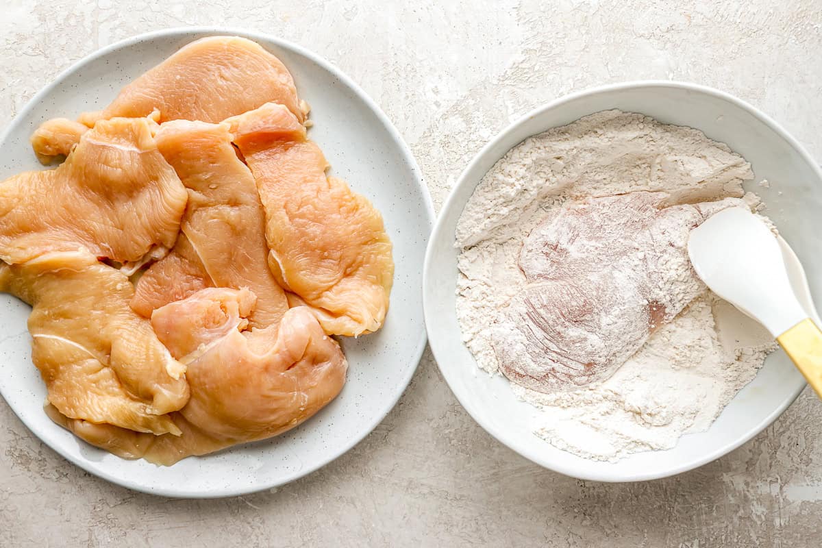 dredging chicken in seasoned flour with a spatula.