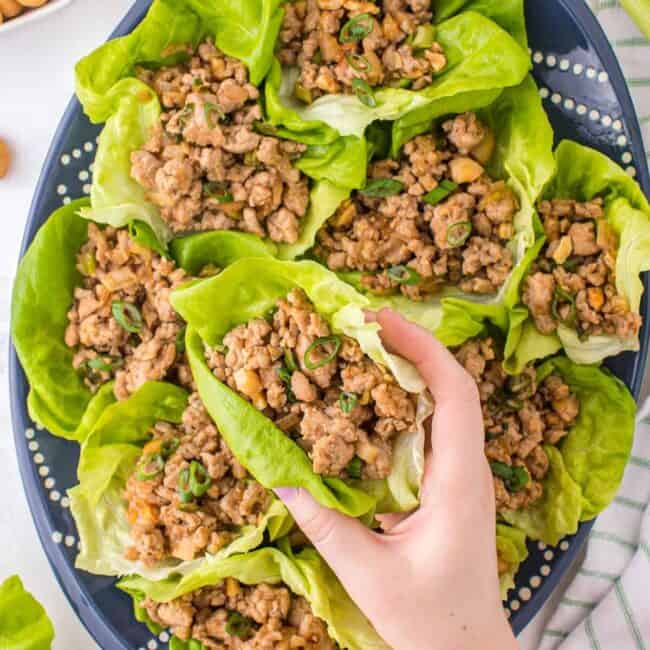 lifting up chicken lettuce wrap from platter