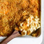 overhead view of a spoonful of baked mac and cheese resting in a casserole dish.
