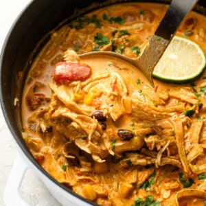 scooping chicken enchilada soup from a dutch oven with a ladle.