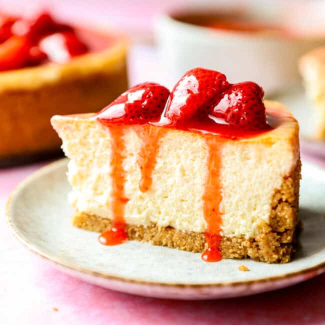 side view of a slice of cheesecake with strawberry sauce on top.